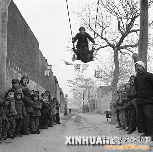 1954年春节，河北省晋县五区刘靳庄的两位农村小姑娘快把秋千荡得和树梢头一般高了。